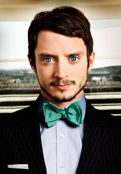 a man with blue eyes wearing a green bow tie