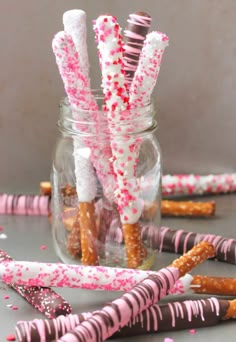 some pink and white sprinkles are in a jar with candy canes