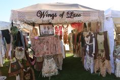 an open tent with many different pieces of clothing hanging on it's sides and the words wings of lace above them