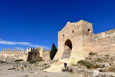 an old stone castle sitting on top of a rocky hill next to a blue sky