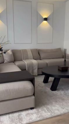 a living room with a couch, coffee table and two vases on the wall