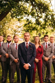 a group of people standing next to each other in front of a tree and grass field