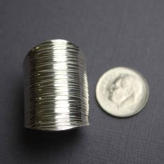 a coin sitting next to a silver coil