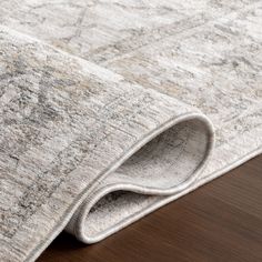 an area rug with wood flooring on top of it and a wooden table in the background