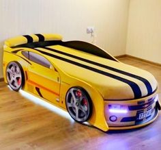 a yellow car shaped bed sitting on top of a hard wood floor next to a wall