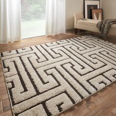 a living room with a large rug on the floor next to a chair and window