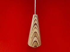 a wooden object hanging from a string on a red wall