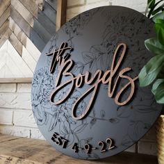 a sign that says the boyds on it next to a potted plant in front of a brick wall