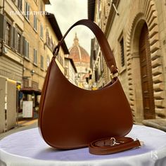 This bag has been made of the best genuine leather by local master crafters of Florence in Italy, designed for women who only accept premium Italian quality and luxury leather bags and modern Italian fashion. . Size: Width:27cm/10.7inch Height:15cm/6 inch Depth: 7cm/3inch Color: Dark Brown . The story of this bag: Looking for the perfect birthday gift for his girlfriend, our protagonist sets out on a mission to find something special. He browses through countless stores, but nothing seems to catch his eye. Until one day, he stumbles upon an Etsy shop selling elegant handmade red leather tote bags made in Florence, Italy. Intrigued, he decides to take a closer look and is blown away by the beauty and quality of the bags. He knows this is the perfect gift for his girlfriend, who loves timele Luxury Brown Faux Leather Shoulder Bag, Luxury Brown Faux Leather Bag, Luxury Faux Leather Shoulder Bag With Leather Lining, Elegant Soft Leather Shoulder Bag Gift, Luxury Brown Shoulder Bag With Smooth Grain, Elegant Bags With Leather Backing For Everyday Use, Luxury Smooth Grain Shoulder Bag As Gift, Elegant Cognac Soft Leather Shoulder Bag, Elegant Everyday Bags With Leather Backing