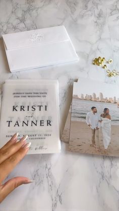 a person holding a book next to two photos on a marble table with gold accents