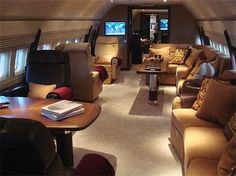 the inside of an airplane with couches and tables