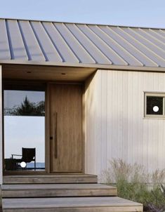 a small white house with a metal roof and wooden steps leading to the front door