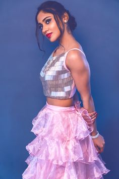 a woman in a pink skirt and crop top posing with her hands on her hips