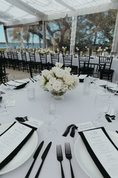 a table set up with black and white place settings, silverware and napkins