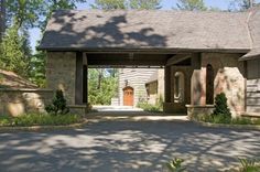 an entrance to a home with stone pillars and brick walls, surrounded by greenery