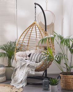 a hanging chair in the corner of a room with potted plants and rugs