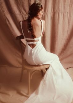 a woman in a white dress sitting on a chair with her back to the camera