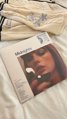 a magazine laying on top of a bed next to a sweater and mittens