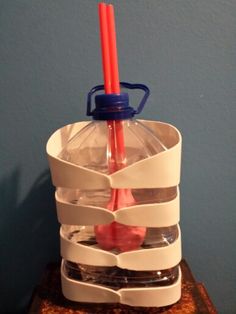 an upside down plastic container with two red candles in it and three clear cups stacked on top