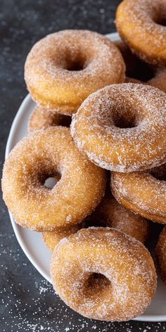 a plate full of sugared donuts on top of a black tablecloth with sprinkles