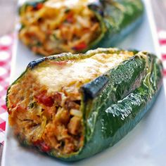 stuffed poblano peppers with cheese and meat on top, sitting on a white plate