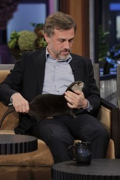 a man sitting in a chair holding a ferret