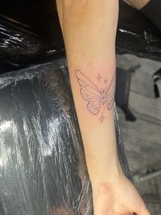 a small butterfly tattoo on the left wrist and right hand is shown in black ink