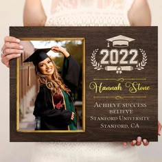 a woman holding up a graduation photo frame with the graduate's name on it