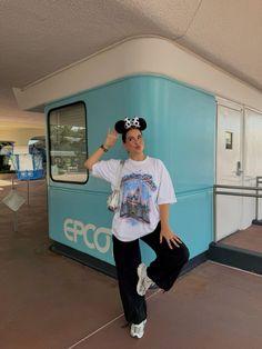 a woman standing in front of a blue train at the epco station with her hand on her head