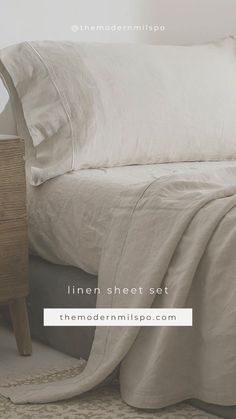 a bed with white sheets and pillows on top of it next to a night stand