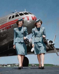 two women in uniforms walking towards an airplane