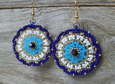 blue and white beaded earrings with gold accents on wooden planks, close up