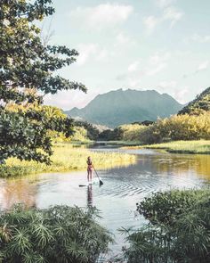 a person standing in the middle of a body of water with mountains in the background