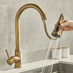 a person's hand is holding the faucet over a sink with water running from it