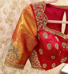 a red blouse with gold and green details on the back, hanging from a hanger