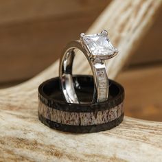 two wedding rings sitting on top of each other in front of a piece of wood