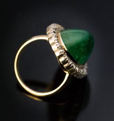 This antique ring from the early 1900s features a big cabochon cut natural emerald of a nice color surrounded by old cushion cut diamonds (H-I color, SI clarity) set in silver over 14K gold. The emerald measures 21.2 x 13 x 9.3 mm and is approximately 19.17 ct. Estimated total diamond weight is 2.20 ct. Ring size 7.25 (18 mm) sizable Elegant Domed Emerald Ring Gift, Elegant Domed Emerald Ring, Antique Diamond Cabochon Rings, Vintage Emerald Ring With Single Cut Diamonds, Elegant Round Emerald Dome Ring, Elegant Emerald Dome Ring, Vintage Cabochon Emerald Ring For Wedding, Vintage Diamond Cabochon Rings, Vintage Diamond Rings With Cabochon