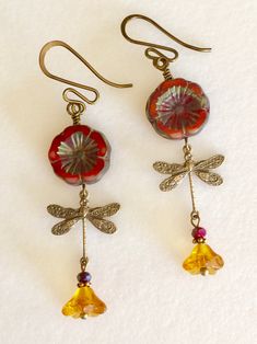 "Adorable red/orange Picasso Czech glass Hawaiian flowers with topaz bellflowers and vintage bronze stamped dragonfly charms. Red/orange 14 mm Czech flowers with rustic Picasso finish are wire wrapped in vintage bronze with 6 x 9 mm translucent topaz yellow bellflowers accented with tiny burnt orange crystals. Lightweight dangles hang on vintage bronze French ear wires. Total drop is 2 1/4\"." Beaded Dragonfly Earrings, Red Whimsical Nickel-free Earrings, Whimsical Red Nickel-free Earrings, Vintage Red Copper Earrings, Whimsical Red Flower Jewelry, Red Bohemian Soldered Earrings, Bohemian Red Soldered Earrings, Vintage Czech Glass Flower Earrings For Gift, Vintage Czech Glass Flower Earrings Gift