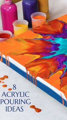 an orange book with blue and purple paint on it, surrounded by other art supplies