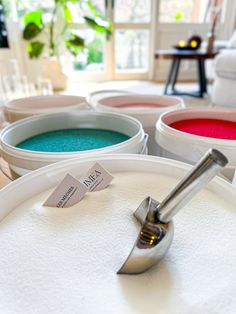 there are several different colored bowls on the table with spoons in them and one is empty