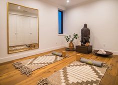 a living room with wooden floors and rugs on the floor next to a large mirror