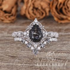 a black diamond ring sitting on top of a wooden table next to some brown roses