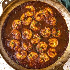 a pan filled with shrimp and sauce on top of a table