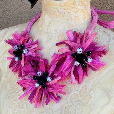 a pink and black flower necklace on top of a mannequin's torso