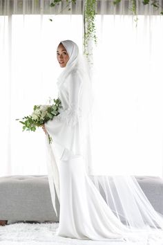 a woman in a white wedding dress holding a bouquet of flowers and wearing a veil