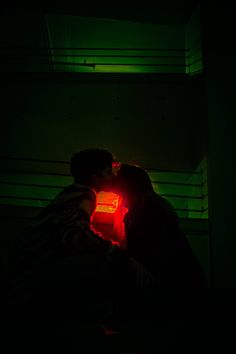 two people kissing in the dark with green light