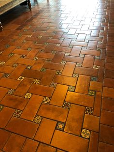 a bench sitting on top of a wooden floor next to a tiled floor covered in tiles