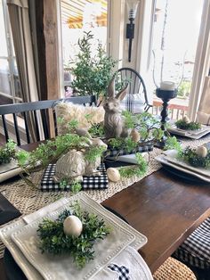 the table is set with plates and place settings for two rabbits sitting on top of each other