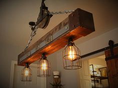 three light fixtures hanging from a beam with chains and caged lights on it's sides