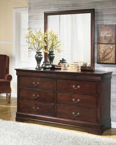 a dresser with two vases on top of it and a mirror over the top